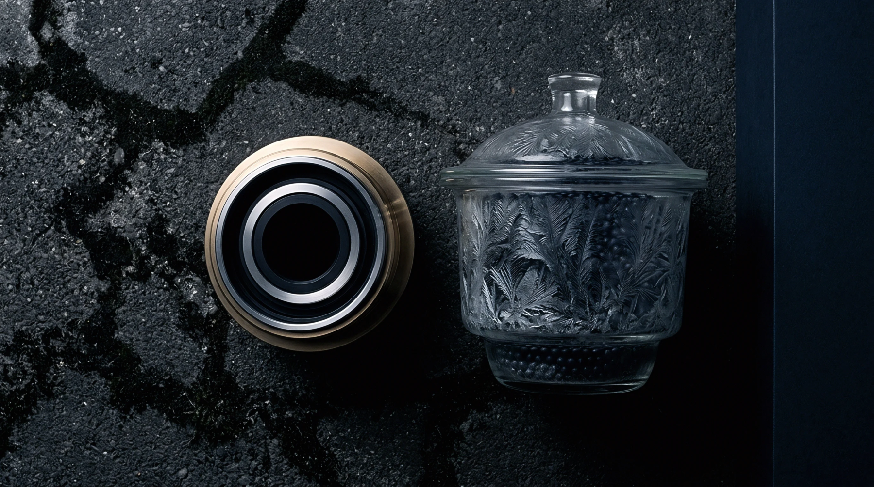 Precision steel bearing and frosted glass vessel rest upon cracked dark asphalt during industrial partnership development phases.