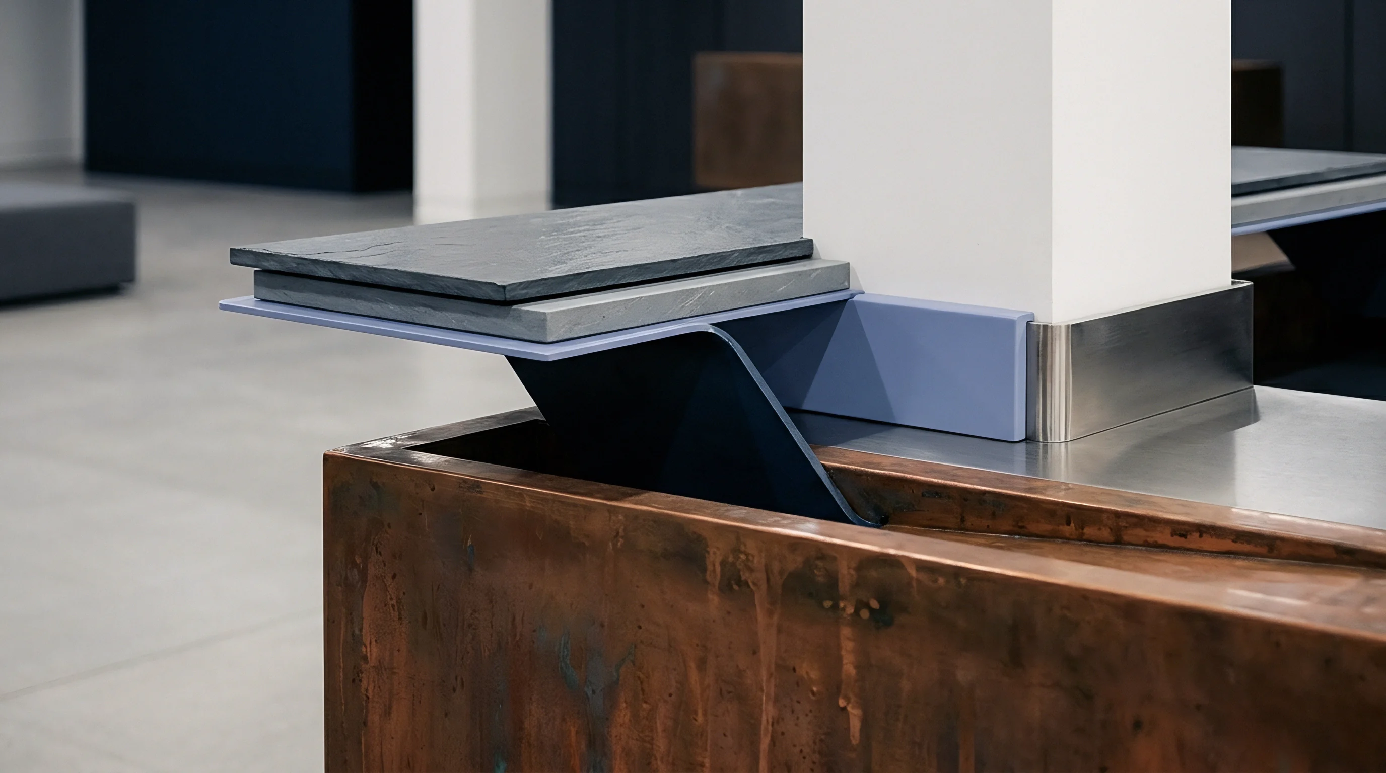 A static display showcases a modular construction of various industrial materials including rough slate, engineered panels, polished metal, and weathered copper elements.