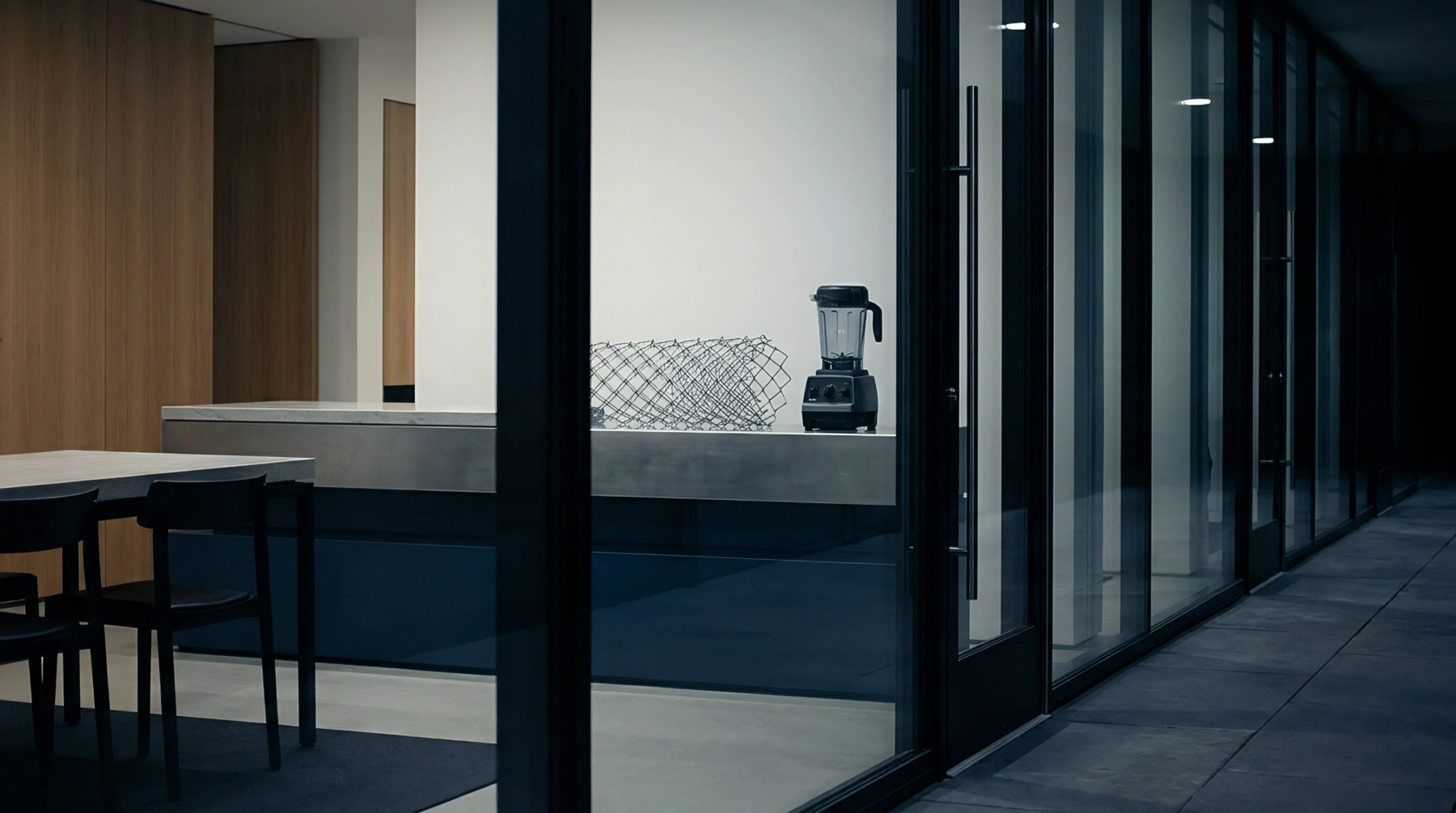 Glass partitions and concrete flooring enclose a minimalist production planning office housing modular cabinetry and architectural metal framing elements.